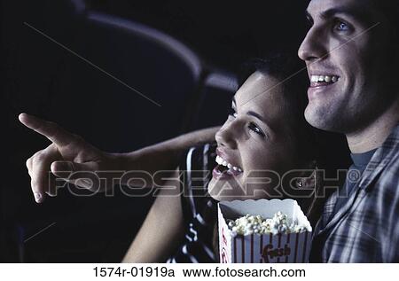 Stock Image - Close-up of a young couple in a theater watching a movie. Fotosearch