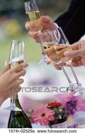 Stock Image - Close-up of peoples hands toasting with glasses of champagne. Fotosearch