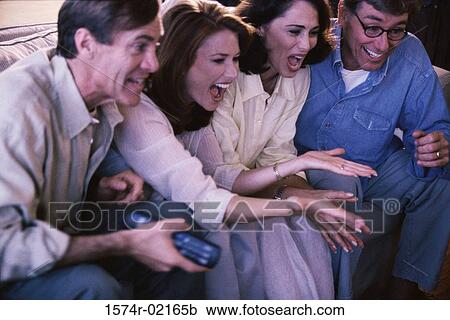 Close-up of two mid adult couples watching television View Large Photo Image Stock Image - Close-up of two mid adult couples watching television. Fotosearch