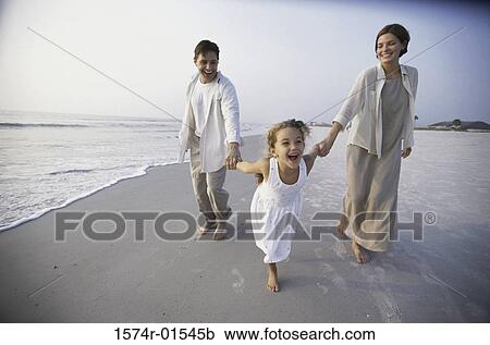 Stock Image - Couple with their daughter on the beach. Fotosearch
