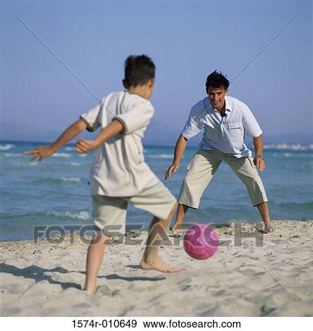 Stock Photo - Father and his son playing with a ball on the beach. Fotosearch
