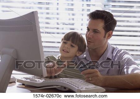 Father and his son sitting in front of a computer View Large Photo Image Stock Image - Father and his son sitting in front of a computer. Fotosearch