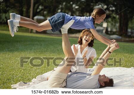 Father and mother playing with their daughter on a lawn View Large Photo Image Stock Image - Father and mother playing with their daughter on a lawn. Fotosearch