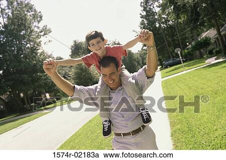 Father carrying his son on his shoulders View Large Photo Image Stock Image - Father carrying his son on his shoulders. Fotosearch