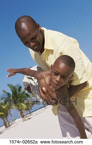 Father carrying his son on the beach View Large Photo Image Stock Image - Father carrying his son on the beach. Fotosearch