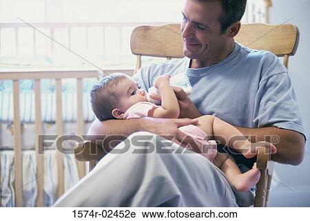 Stock Image - Father feeding his baby boy. Fotosearch