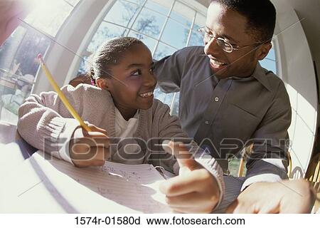 Stock Image - Father helping his daughter with her homework. Fotosearch