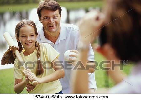 Stock Image - Father holding a baseball bat standing with his daughter. Fotosearch
