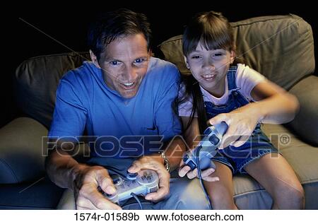 Stock Image - Father playing video games with his daughter. Fotosearch