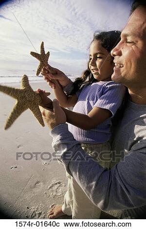 Father showing his daughter a starfish on the beach View Large Photo Image Stock Image - Father showing his daughter a starfish on the beach. Fotosearch