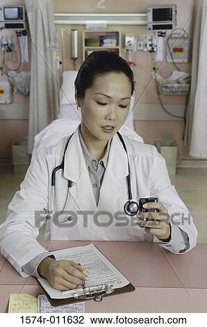 Female doctor looking at a pager View Large Photo Image Stock Image - Female doctor looking at a pager. Fotosearch