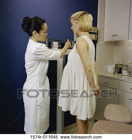 Stock Photography - Female nurse weighing a female patient. Fotosearch