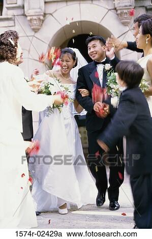 Stock Image - Flower petals being thrown on a bride and groom. Fotosearch