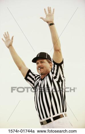 Stock Image - Football referee whistling with his arms raised. Fotosearch