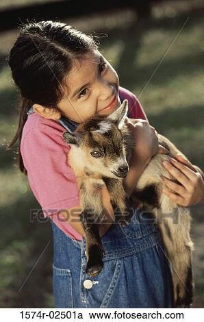 Stock Image - Girl holding a kid goat in her arms. Fotosearch