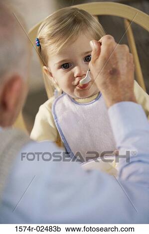 Stock Image - Grandfather feeding his granddaughter. Fotosearch
