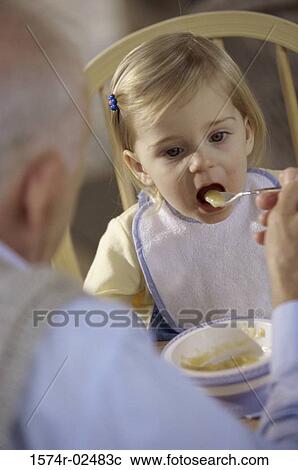 Stock Image - Grandfather feeding his granddaughter. Fotosearch