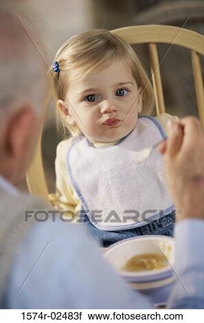 Stock Image - Grandfather feeding his granddaughter. Fotosearch
