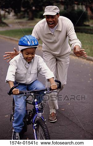 Grandfather helping his grandson ride a bicycle View Large Photo Image Stock Image - Grandfather helping his grandson ride a bicycle. Fotosearch
