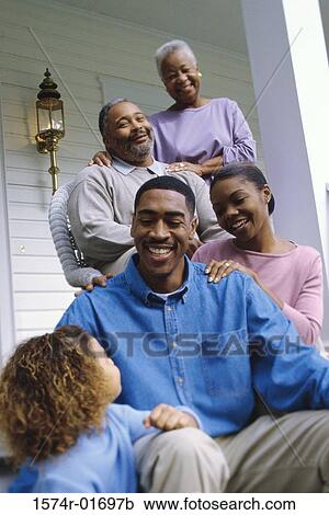 Stock Image - Grandparents sitting on the front porch with their son and granddaughter. Fotosearch