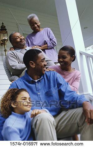 Stock Image - Grandparents sitting on the front porch with their son and granddaughter. Fotosearch