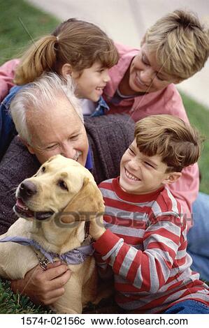 Stock Image - Grandparents with their grandson and granddaughter holding their dog. Fotosearch