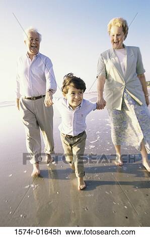 Grandson walking at the beach with his grandparents View Large Photo Image Stock Image - Grandson walking at the beach with his grandparents. Fotosearch