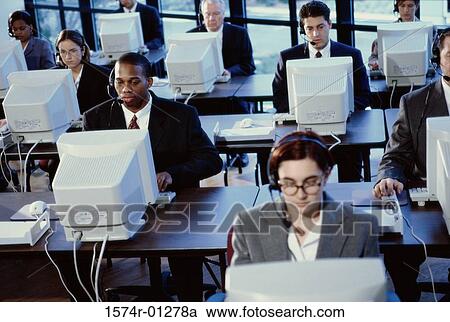 Stock Image - Group of business executives wearing headsets working on computers. Fotosearch