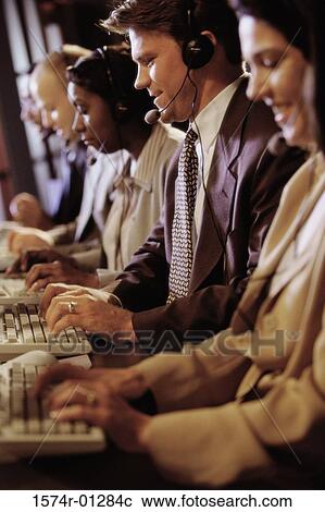Stock Image - Group of business executives wearing headsets working on computers. Fotosearch