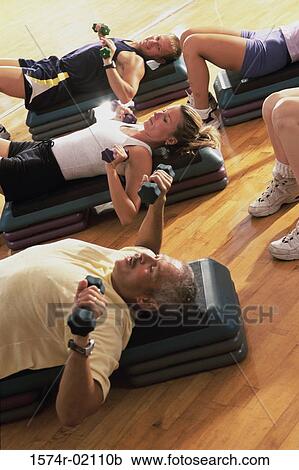Stock Image - Group of people exercising in a step aerobics class. Fotosearch