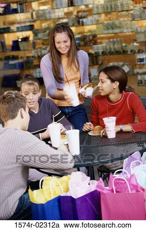 Stock Image - Group of teenagers at a shopping mall cafe. Fotosearch