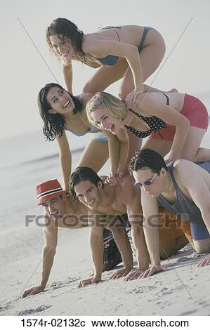 Stock Image - Group of young people making a human pyramid on the beach. Fotosearch