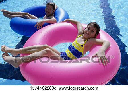 High angle view of a boy and a girl lying on inflatable rings in a swimming pool View Large Photo Image Stock Image - High angle view of a boy and a girl lying on inflatable rings in a swimming pool. Fotosearch
