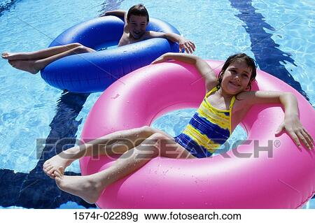 High angle view of a boy and a girl lying on inflatable rings in a swimming pool View Large Photo Image Stock Image - High angle view of a boy and a girl lying on inflatable rings in a swimming pool. Fotosearch