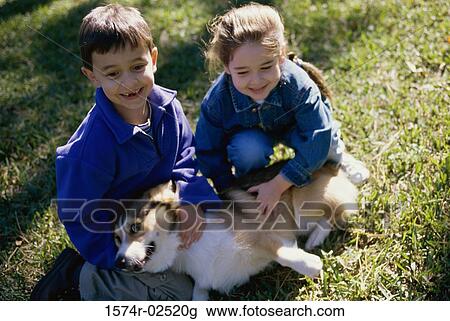 High angle view of a boy and a girl petting their dog View Large Photo Image Stock Image - High angle view of a boy and a girl petting their dog. Fotosearch