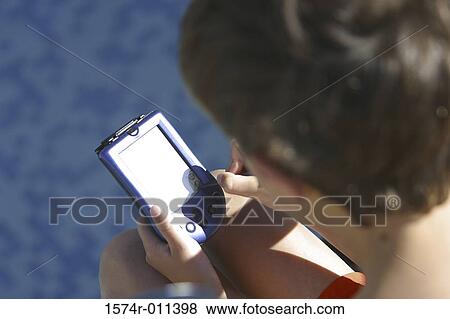 High angle view of a boy holding a hand held device View Large Photo Image Stock Photo - High angle view of a boy holding a hand held device. Fotosearch