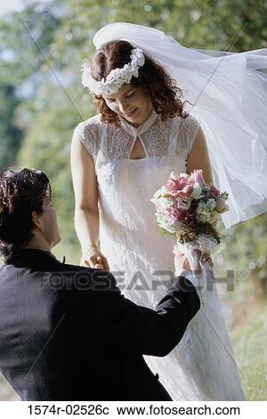 Stock Image - High angle view of a groom giving a bouquet of flowers to his bride. Fotosearch