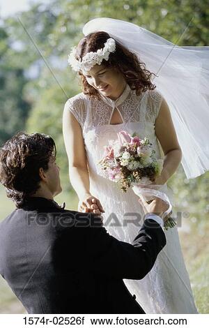 Stock Image - High angle view of a groom giving a bouquet of flowers to his bride. Fotosearch