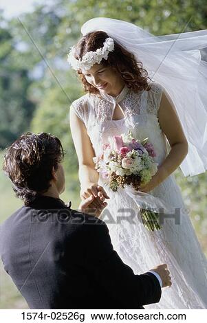 Stock Image - High angle view of a groom giving a bouquet of flowers to his bride. Fotosearch