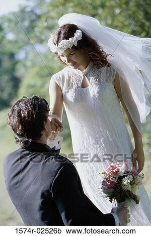 Stock Image - High angle view of a groom kissing his bride's hand. Fotosearch
