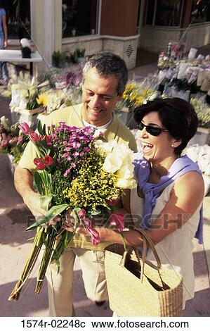 Stock Image - High angle view of a mature couple holding a bouquet of flowers. Fotosearch