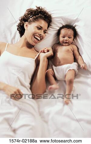 High angle view of a mother lying on a bed with her baby boy View Large Photo Image Stock Image - High angle view of a mother lying on a bed with her baby boy. Fotosearch