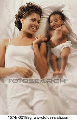 High angle view of a mother lying on a bed with her baby boy View Large Photo Image Stock Image - High angle view of a mother lying on a bed with her baby boy. Fotosearch