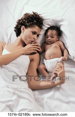 High angle view of a mother lying on a bed with her baby boy View Large Photo Image Stock Image - High angle view of a mother lying on a bed with her baby boy. Fotosearch