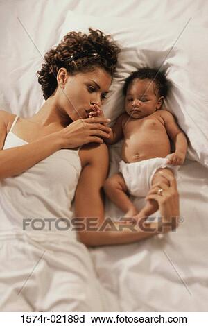 High angle view of a mother lying on a bed with her baby boy View Large Photo Image Stock Image - High angle view of a mother lying on a bed with her baby boy. Fotosearch