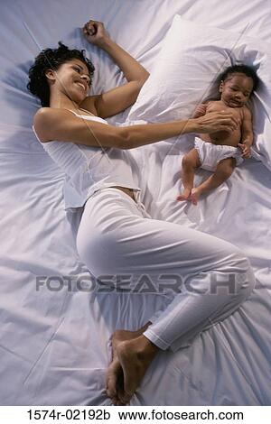 High angle view of a mother lying on a bed with her baby boy View Large Photo Image Stock Image - High angle view of a mother lying on a bed with her baby boy. Fotosearch