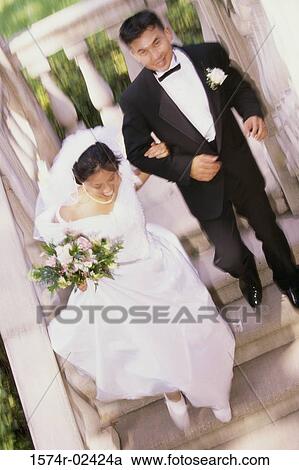 Stock Image - High angle view of a newlywed couple walking down stairs. Fotosearch