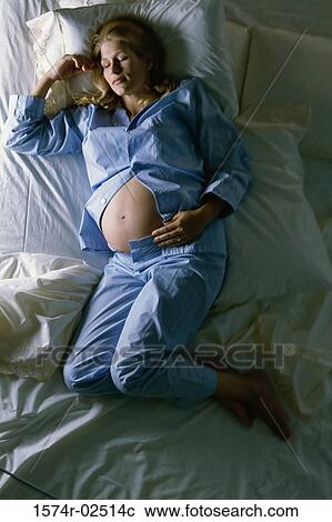 High angle view of a pregnant woman sleeping on a bed View Large Photo Image Stock Image - High angle view of a pregnant woman sleeping on a bed. Fotosearch