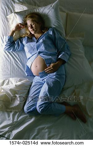 High angle view of a pregnant woman sleeping on a bed View Large Photo Image Stock Image - High angle view of a pregnant woman sleeping on a bed. Fotosearch