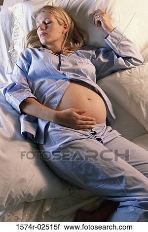 High angle view of a pregnant woman sleeping on a bed View Large Photo Image Stock Image - High angle view of a pregnant woman sleeping on a bed. Fotosearch